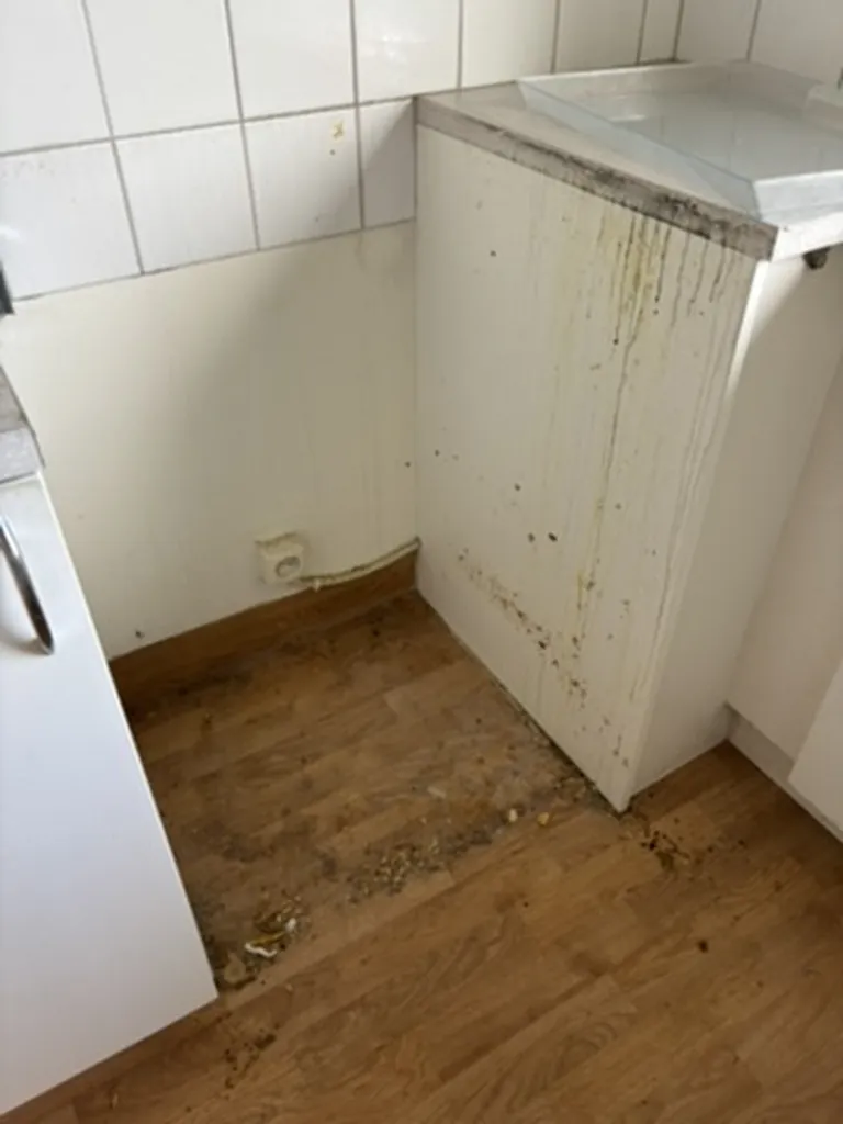 Space behind the stove before cleaning, with dust and debris